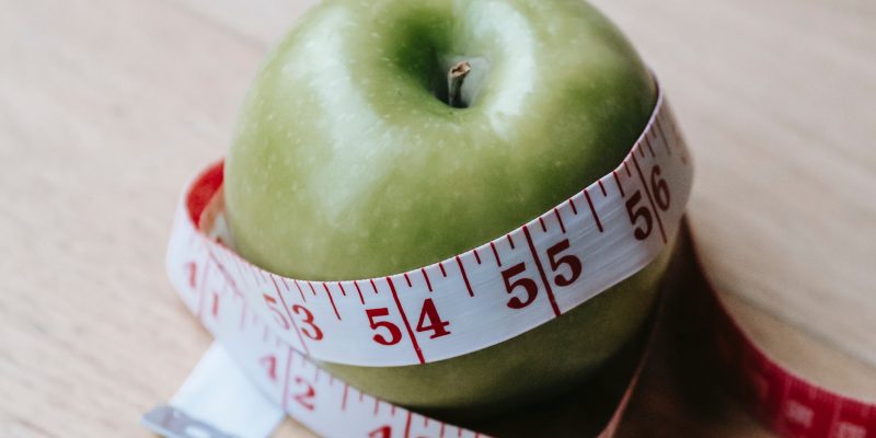 Picture of a green apple wrapped by a measuring tape